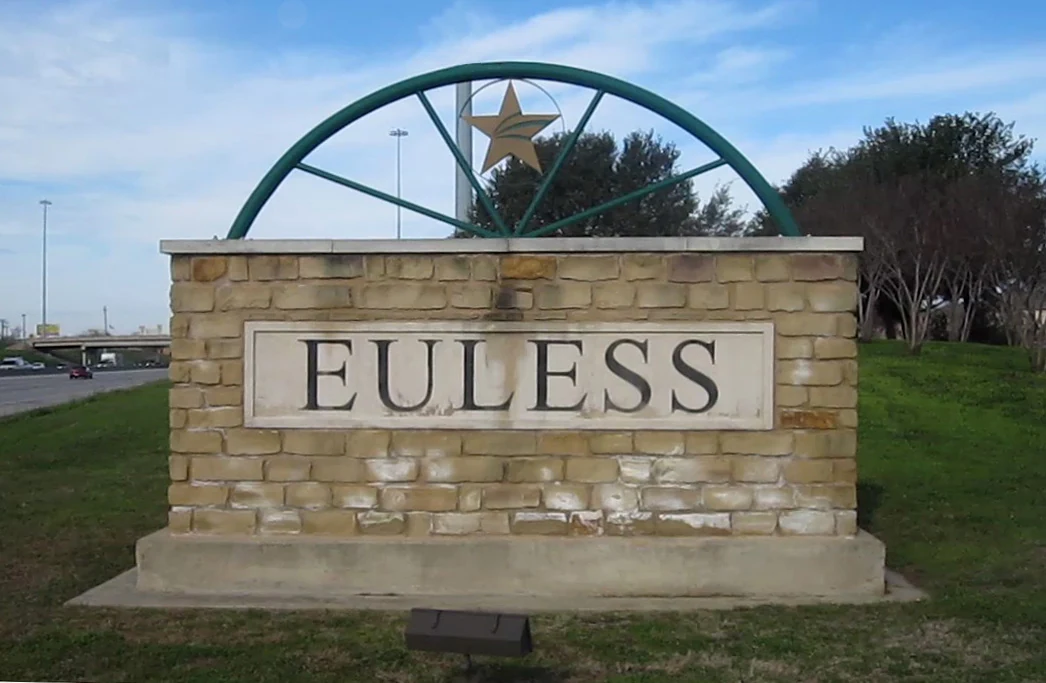 Stone Euless welcome sign with a star and green metal arch